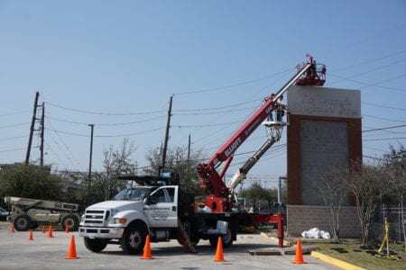 Sign experts performing maintenance on Houston custom signs