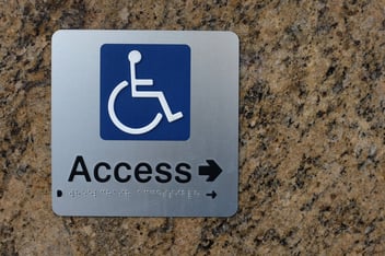 A disable access sign showing the direction with Braille
