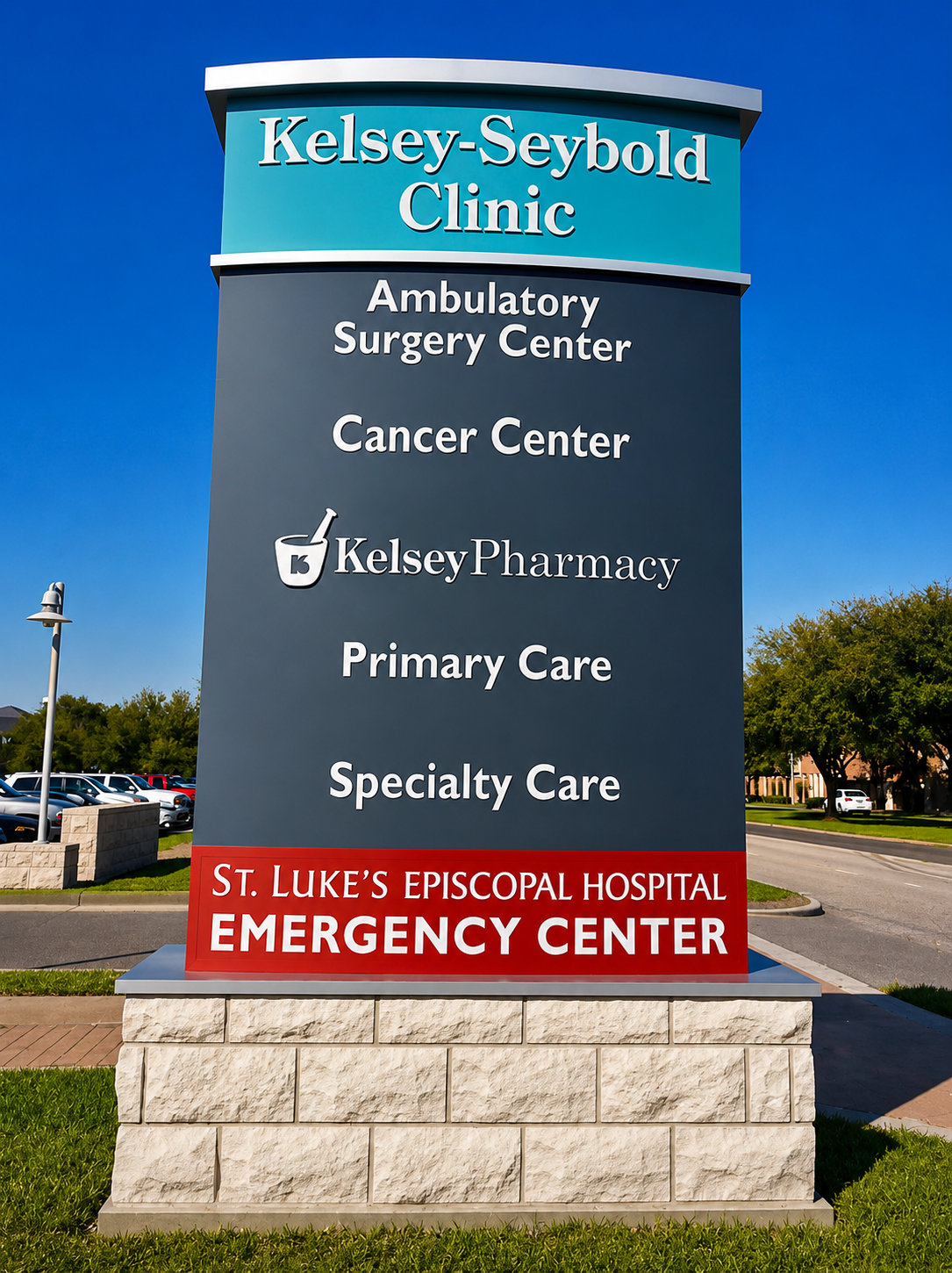 Enhanced monument sign for Kelsey-Seybold Clinic displaying healthcare services including ambulatory surgery, cancer care, pharmacy, primary care, specialty care, and emergency services outside a medical campus.
